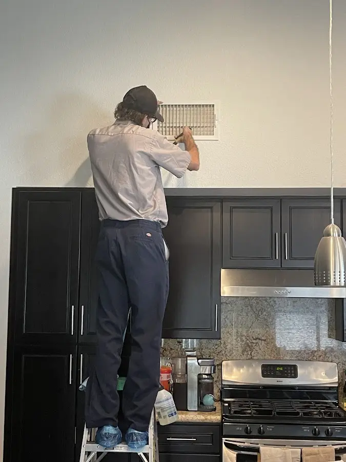 Technician inspecting an air vent during HVAC service in Martinsville
